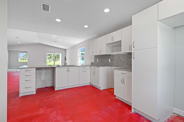 kitchen featuring kitchen peninsula, sink, white cabinets, and lofted ceiling