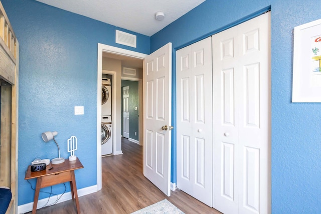 interior space featuring stacked washing maching and dryer, hardwood / wood-style floors, and a closet