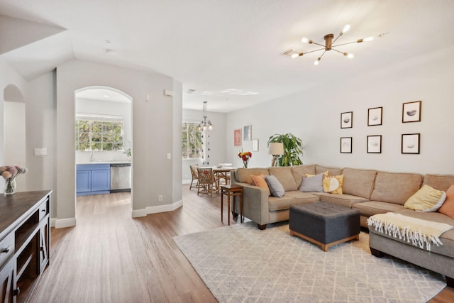 living room featuring wood-type flooring, lofted ceiling, and a notable chandelier