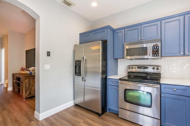 kitchen featuring light wood-type flooring, blue cabinets, backsplash, and stainless steel appliances