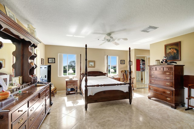 bedroom with a textured ceiling, light tile patterned floors, ceiling fan, and a closet