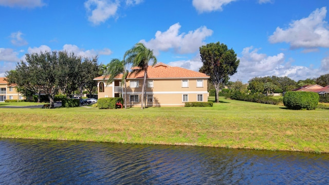 back of house with a lawn and a water view