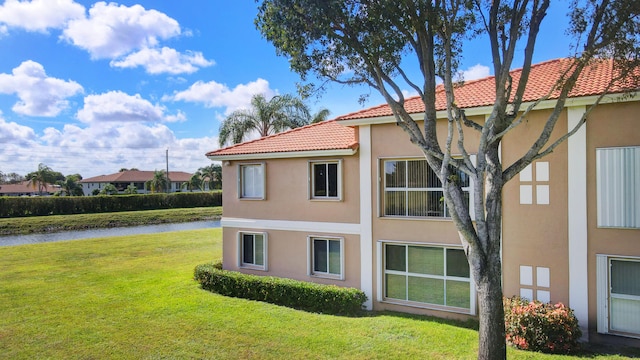 view of home's exterior with a water view and a lawn