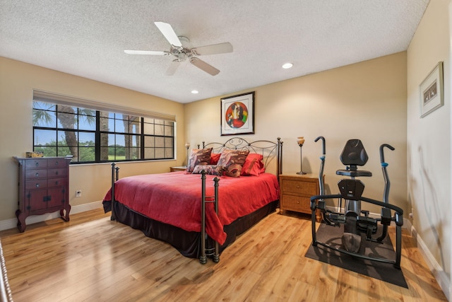 bedroom with ceiling fan, light hardwood / wood-style floors, and a textured ceiling