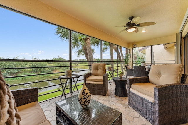 sunroom / solarium featuring ceiling fan and a water view