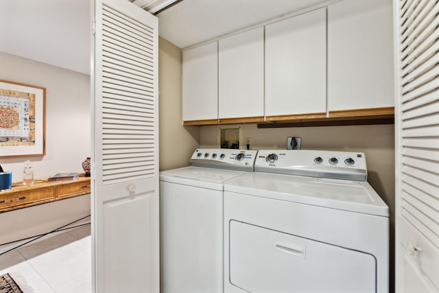 laundry area with washer and clothes dryer, light tile patterned flooring, and cabinets