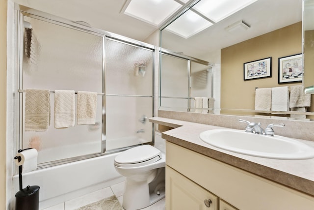 full bathroom with tile patterned floors, shower / bath combination with glass door, vanity, and toilet