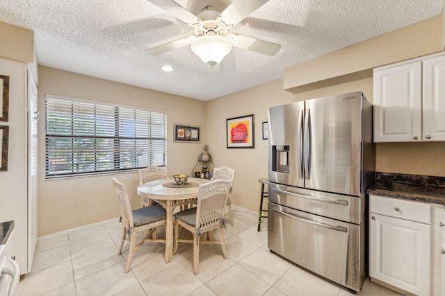 tiled dining space with ceiling fan and a textured ceiling