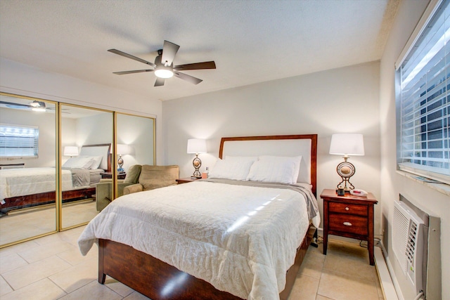 bedroom featuring light tile patterned floors, a wall unit AC, a closet, and ceiling fan