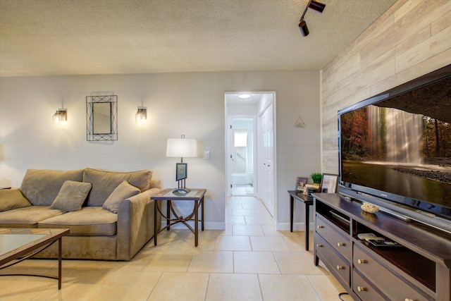 living room with wooden walls, light tile patterned floors, and a textured ceiling