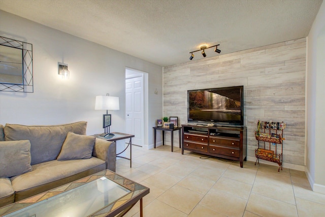 living room with rail lighting, wood walls, light tile patterned floors, and a textured ceiling