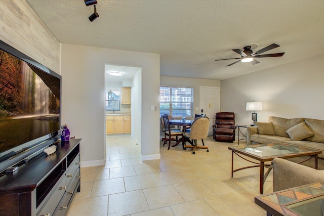 living room with light tile patterned floors, a textured ceiling, ceiling fan, and sink