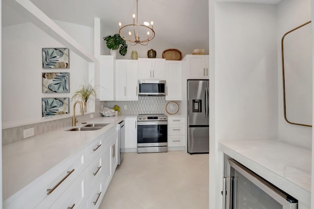 kitchen featuring sink, stainless steel appliances, wine cooler, decorative light fixtures, and white cabinets