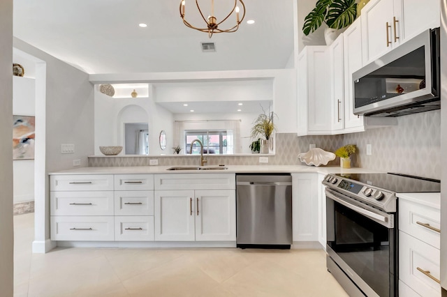 kitchen with sink, stainless steel appliances, a chandelier, decorative backsplash, and white cabinets