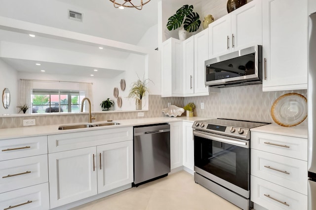 kitchen with white cabinets, appliances with stainless steel finishes, tasteful backsplash, and sink