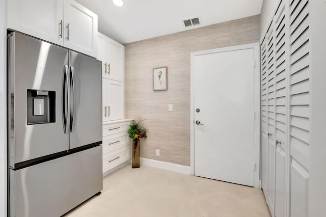 kitchen with stainless steel fridge and white cabinetry