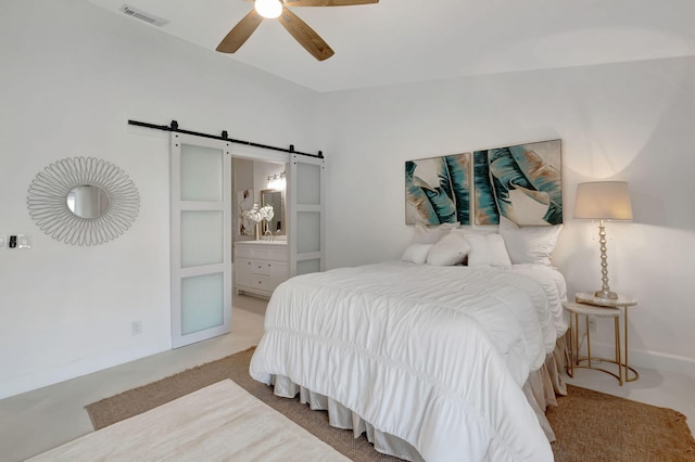 bedroom with ensuite bathroom, a barn door, light carpet, and ceiling fan