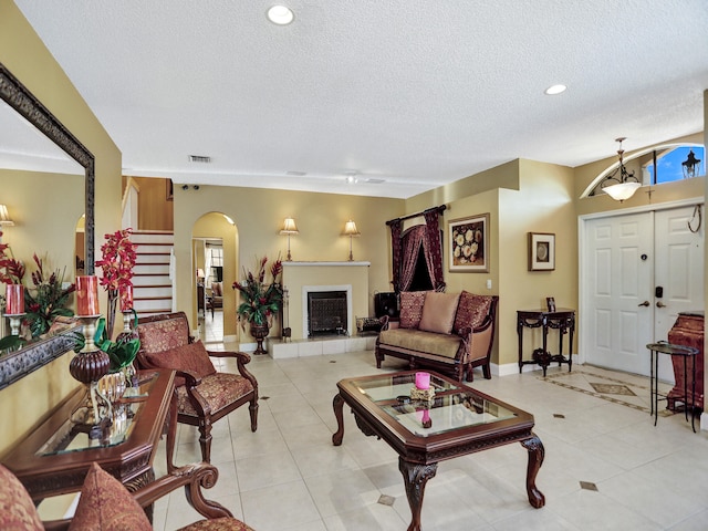 living room with a tile fireplace, light tile patterned floors, and a textured ceiling