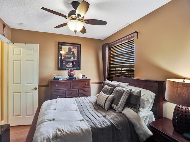 bedroom with light wood-type flooring, a textured ceiling, and ceiling fan