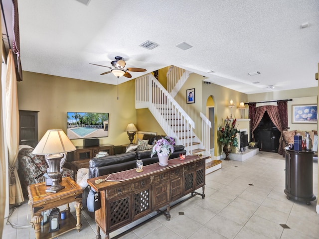 living room with a textured ceiling, light tile patterned floors, and ceiling fan