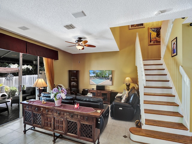 living room with light tile patterned flooring, ceiling fan, and a textured ceiling