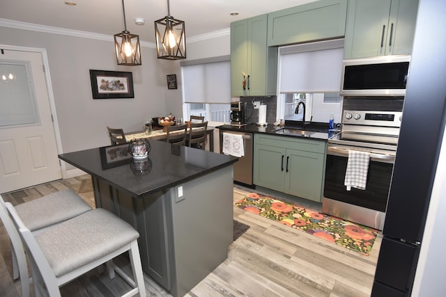 kitchen with green cabinets, sink, a breakfast bar, and appliances with stainless steel finishes