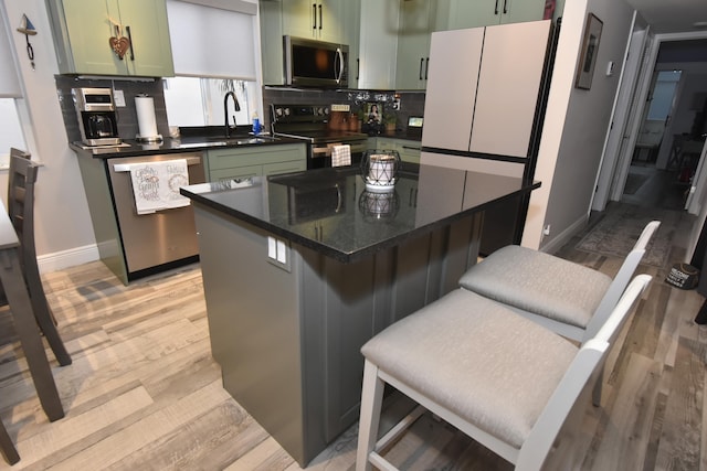 kitchen with stainless steel appliances, sink, backsplash, and green cabinetry