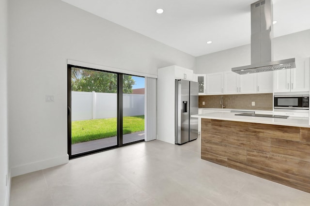 kitchen featuring island exhaust hood, white cabinetry, appliances with stainless steel finishes, backsplash, and sink