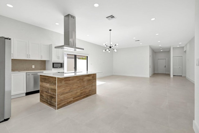 kitchen with island exhaust hood, stainless steel appliances, an inviting chandelier, white cabinets, and a center island