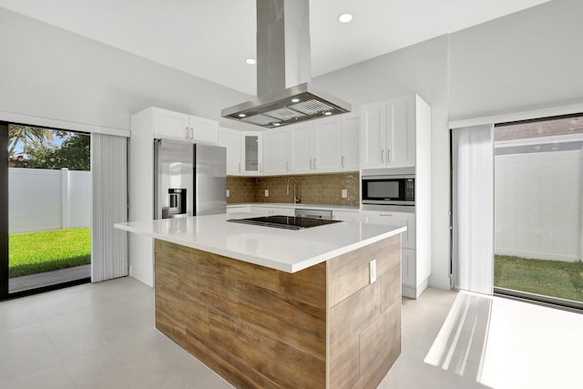 kitchen featuring stainless steel appliances, island range hood, white cabinets, tasteful backsplash, and a kitchen island