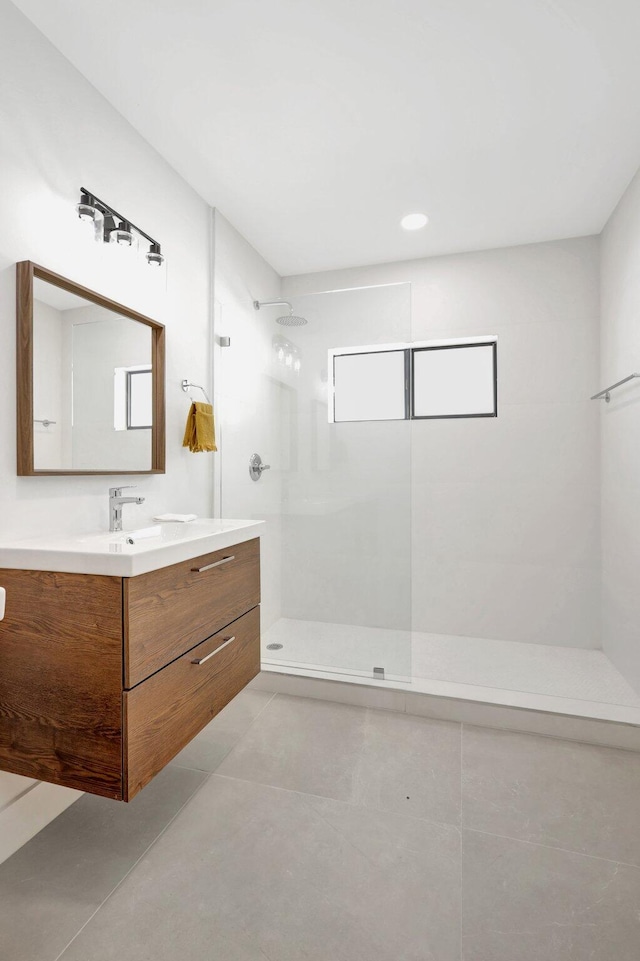 bathroom with tile patterned flooring, vanity, and tiled shower