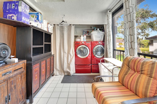 laundry area featuring washing machine and clothes dryer, light tile patterned flooring, and a textured ceiling