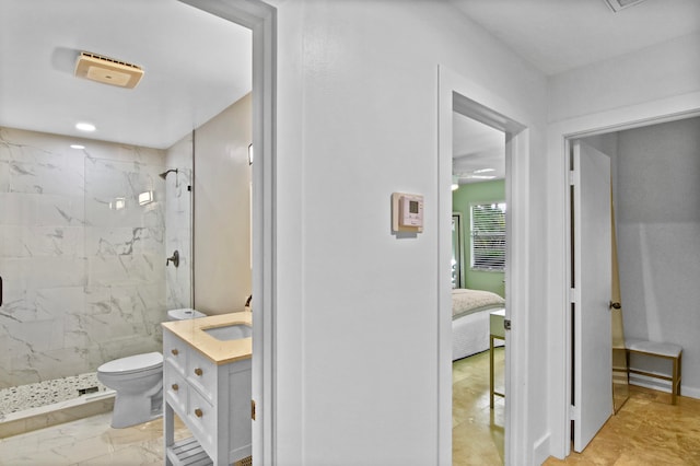 bathroom with toilet, a tile shower, and vanity