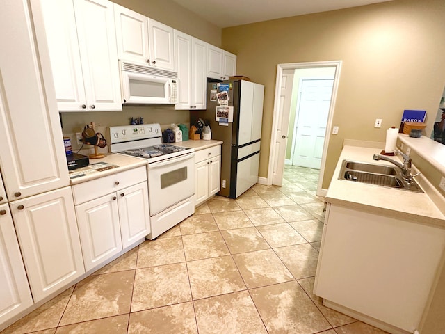 kitchen with light tile patterned flooring, white appliances, white cabinets, and sink