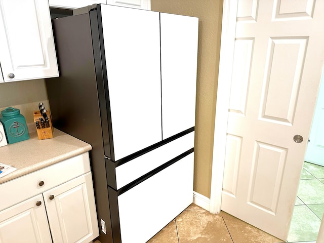 kitchen featuring white cabinets, white fridge, and light tile patterned flooring