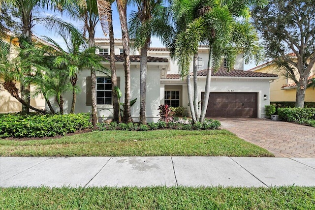 mediterranean / spanish-style house featuring a garage and a front lawn