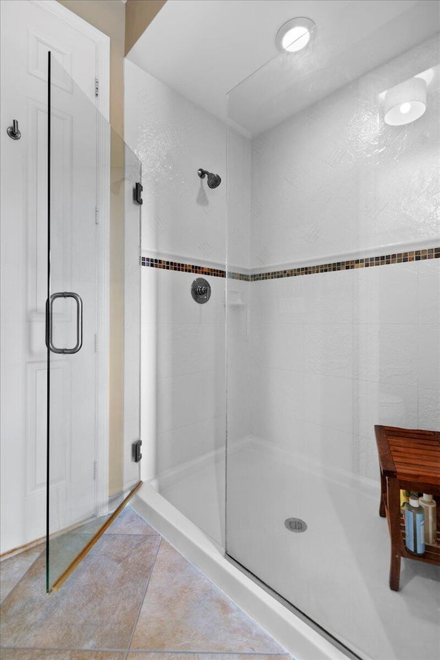 bathroom with a shower with door and tile patterned floors