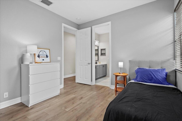 bedroom featuring ensuite bathroom, sink, and light hardwood / wood-style flooring