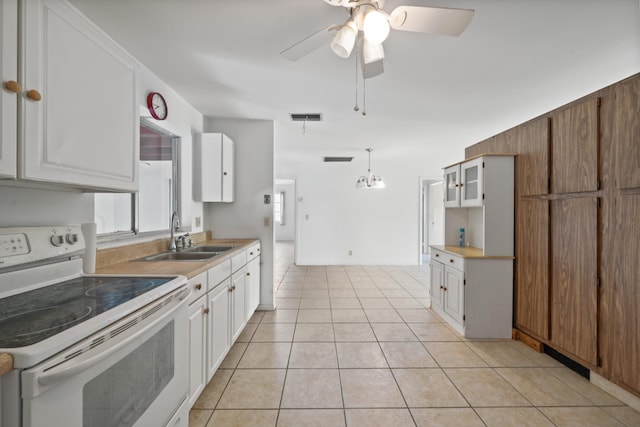 kitchen featuring white cabinets, sink, light tile patterned floors, and electric range