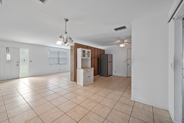 kitchen featuring stainless steel refrigerator, light tile patterned flooring, and ceiling fan with notable chandelier