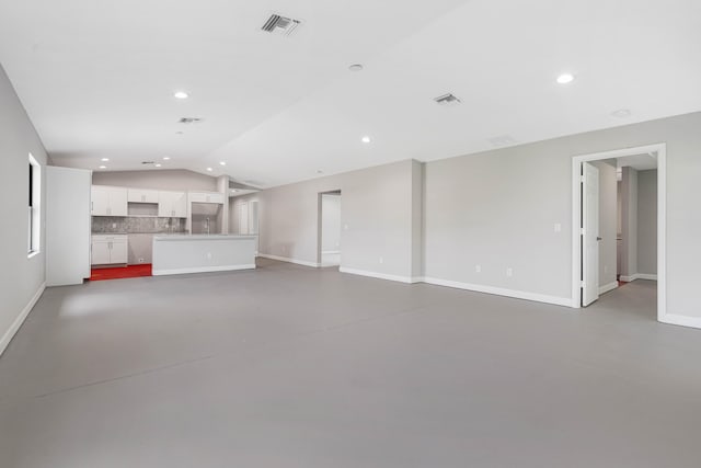 unfurnished living room featuring lofted ceiling and concrete floors