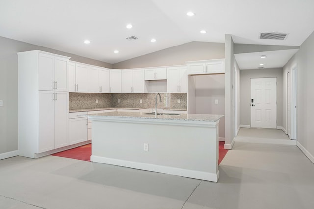 kitchen with a center island with sink, white cabinetry, backsplash, sink, and vaulted ceiling