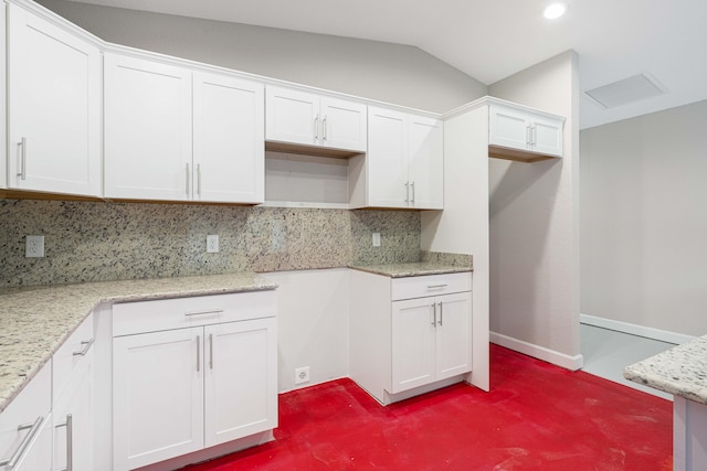 kitchen featuring backsplash, vaulted ceiling, light stone counters, and white cabinets