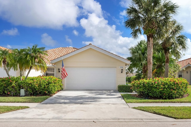 7770 SE Spicewood Cir, Hobe Sound, FL 33455 - view of front of property with concrete driveway, an attached garage, stucco siding, and a tile roof