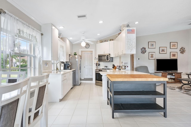 kitchen featuring stainless steel appliances, white cabinets, lofted ceiling, and tasteful backsplash