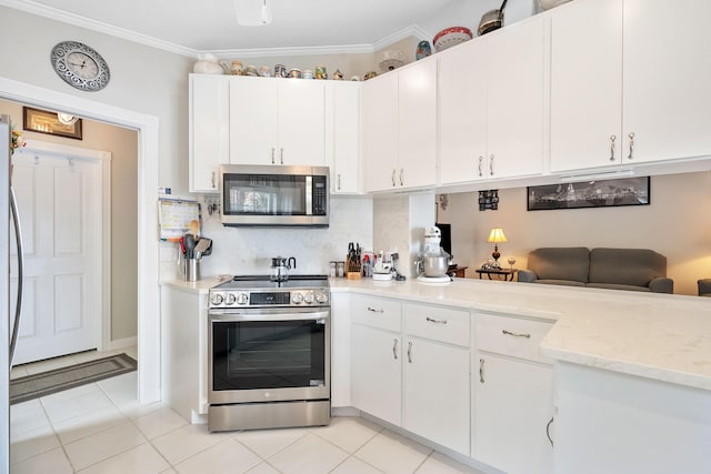 kitchen with white cabinets, light tile patterned floors, ornamental molding, backsplash, and appliances with stainless steel finishes