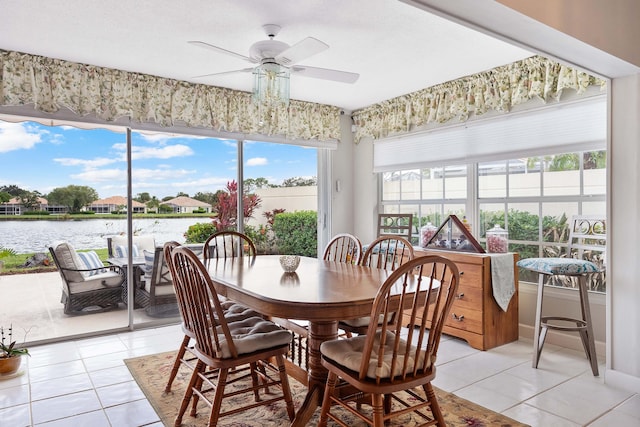 dining room featuring ceiling fan, light tile patterned floors, and a water view