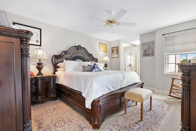 bedroom with light hardwood / wood-style floors, ceiling fan, and a textured ceiling