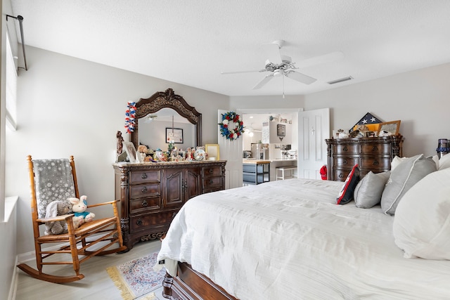 bedroom with ceiling fan, a textured ceiling, and light hardwood / wood-style flooring