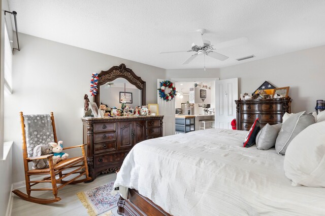 7770 SE Spicewood Cir, Hobe Sound, FL 33455 - bedroom with light wood-style flooring, baseboards, a ceiling fan, and a textured ceiling